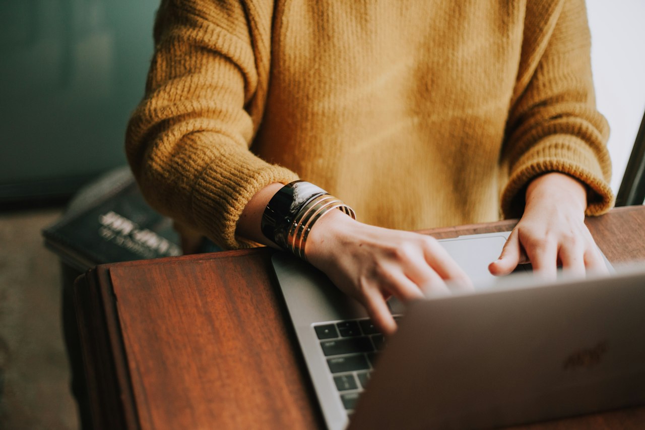 Trabalhador autônomo digitando no notebook em uma mesa de madeira