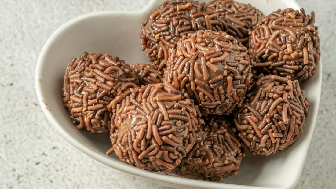 Brigadeiros gourmet com granulado em uma tigela branca em formato de coração