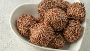 Brigadeiros gourmet com granulado em uma tigela branca em formato de coração Brigadeiros gourmet com granulado em uma tigela branca em formato de coração