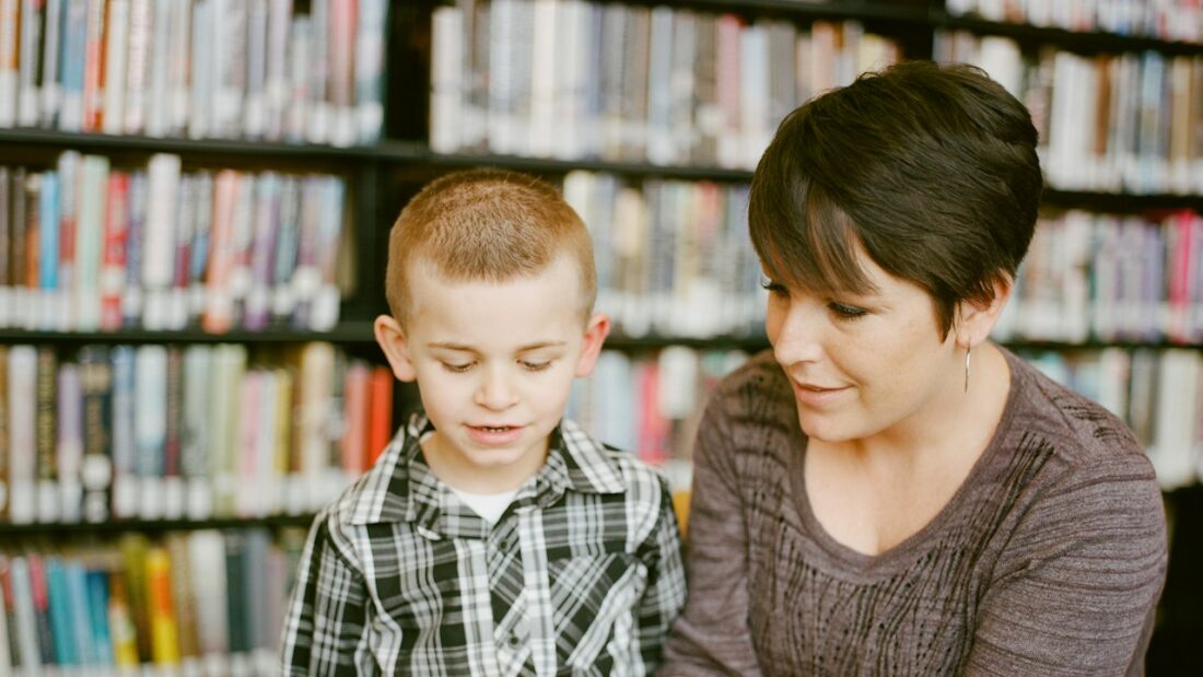 Mãe e filho lendo um livro juntos em uma biblioteca