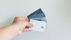 Mão segurando três cartões de crédito em leque sobre fundo claro Mão segurando três cartões de crédito em leque sobre fundo claro