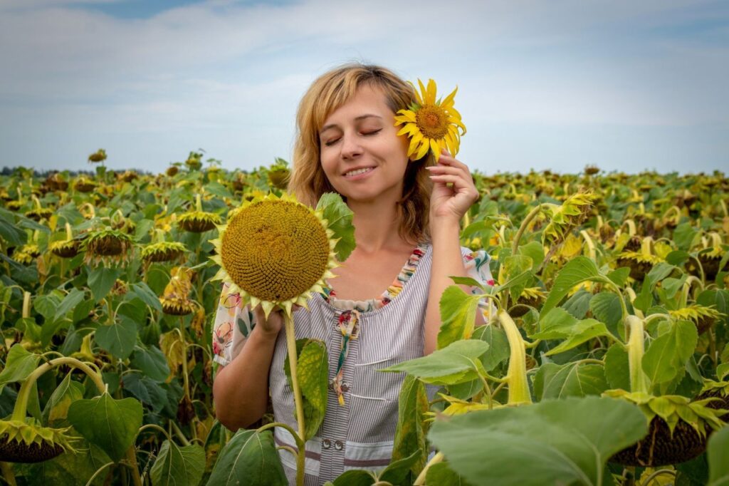 Mulher loira sorrindo com um girassol em um campo de girassóis Mulher loira sorrindo com um girassol em um campo de girassóis