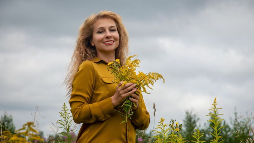 Mulher loira sorrindo com flores do campo nas mãos Mulher loira sorrindo com flores do campo nas mãos