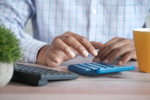 Pessoa usando calculadora sobre a mesa para fazer contas de dívidas