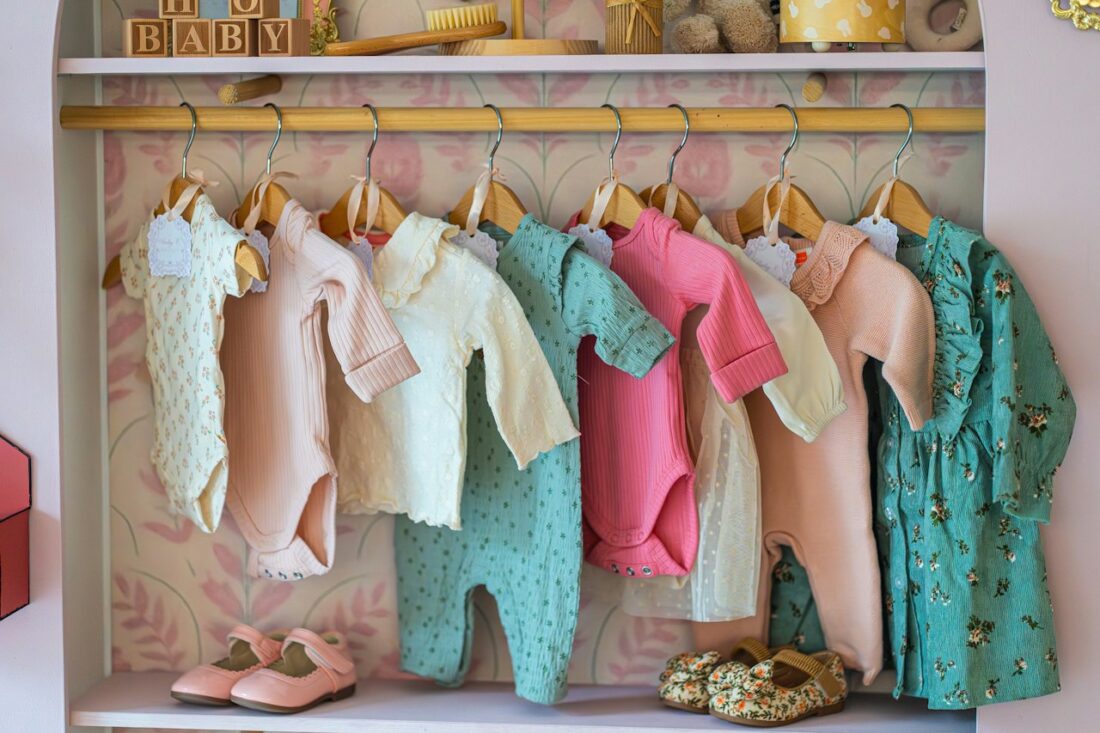 Roupinhas de bebê penduradas em cabides em um quarto infantil
