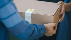 Pessoa entregando uma caixa de papelão com encomenda para envio